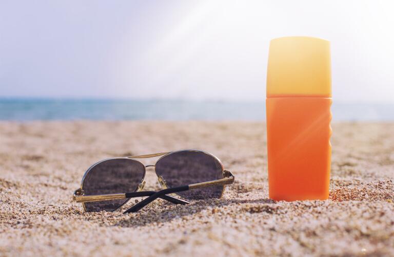 sunscreen-bottle-with-sunglasses-on-beach