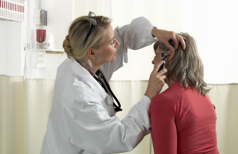 Older Caucasian woman getting ear exam from female Caucasian ear, nose and throat doctor
