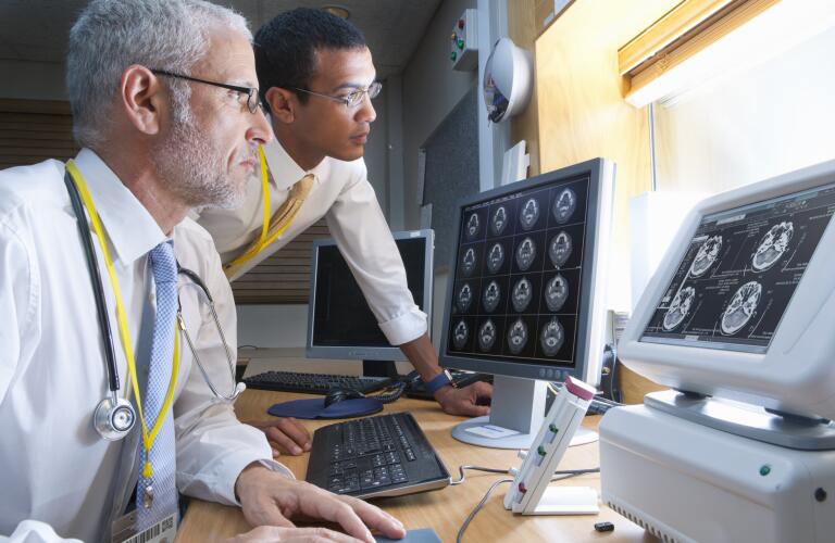 surgeon and radiologist viewing digital brain scan in hospital