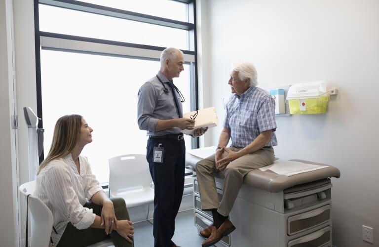 older male patient with his daughter being seen by doctor