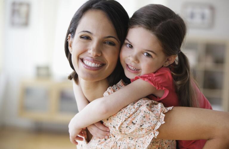 Smiling mother carrying daughter piggyback