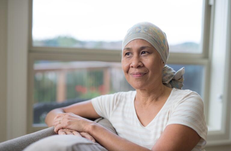 cancer patient sitting by window in head wrap