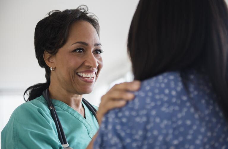 smiling African American female healthcare worker placing hand on unidentified patient