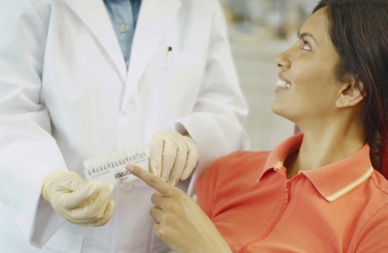 dental patient choosing tooth color sample from dentist