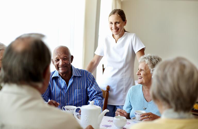 Caretaker with senior people enjoying coffee break