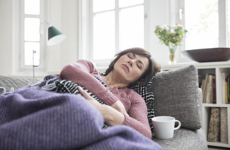 Middle aged woman on couch with stomach pain