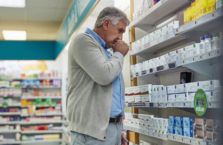 man with cough in pharmacy looking for medicine