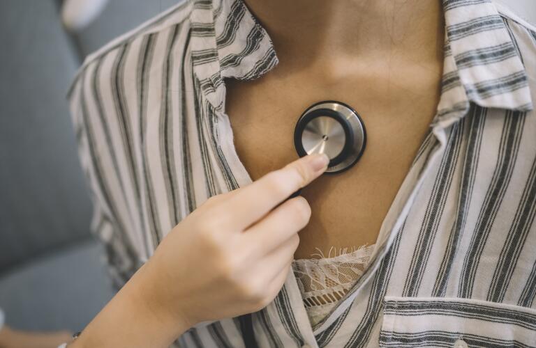 Cropped image of female doctor holding stethoscope on woman's chest