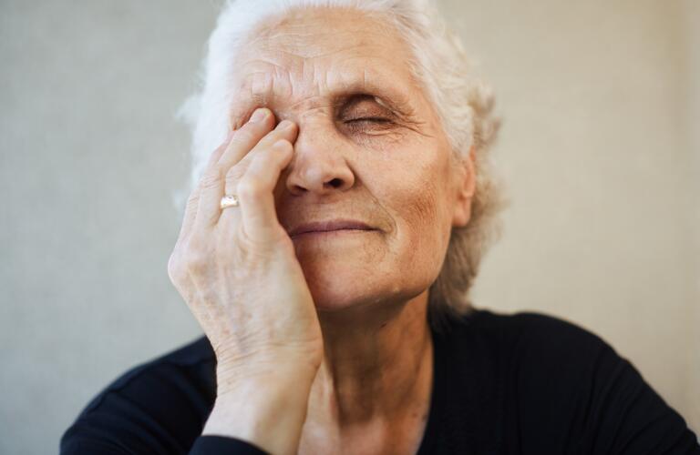 senior woman with one hand over eye