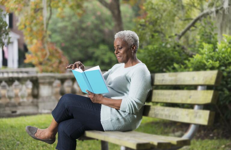 senior-african-american-woman-sitting-on-bench-reading