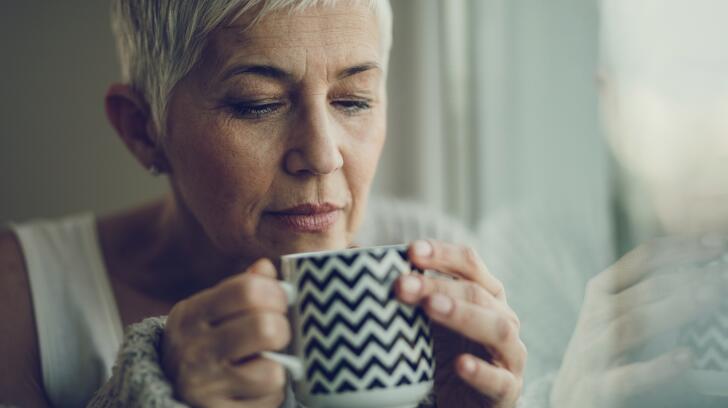 người phụ nữ cao tuổi ngửi cà phê hoặc tách trà
