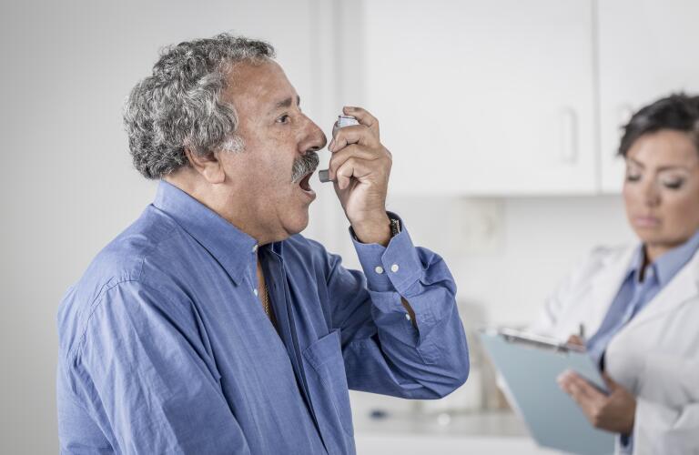 senior man in doctor's office using inhaler