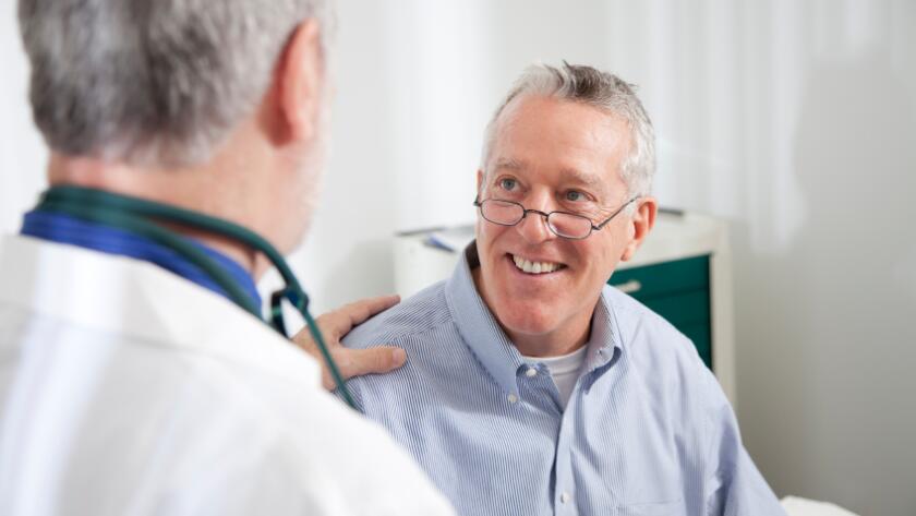 Male doctor with male patient with hand on shoulder