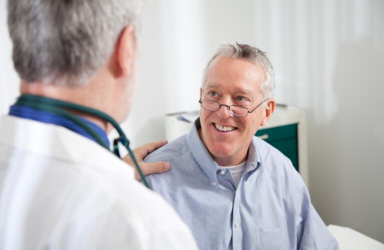 Male doctor with male patient with hand on shoulder