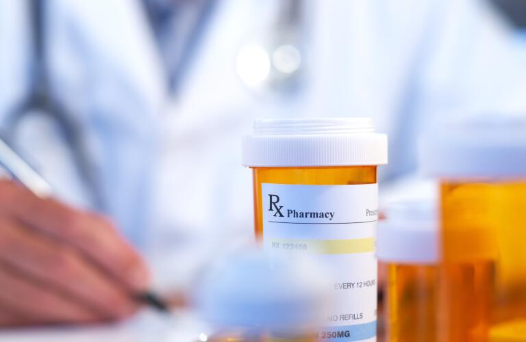 Doctor writing prescription with medicine bottles