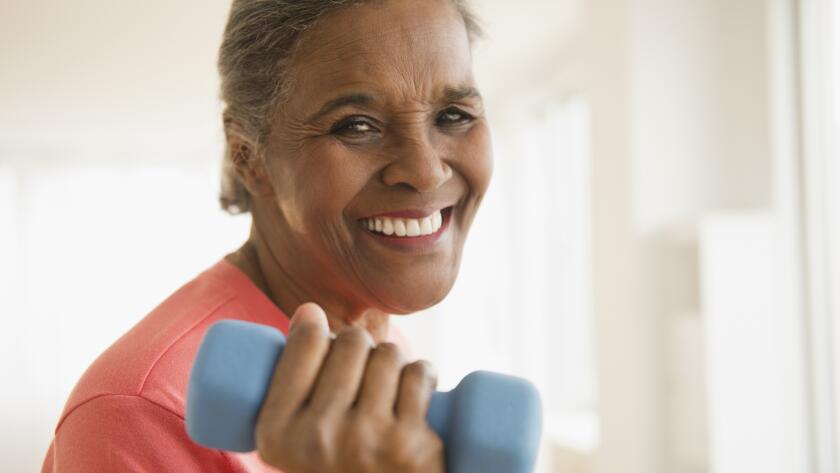 portrait of smiling senior woman lifting hand weight