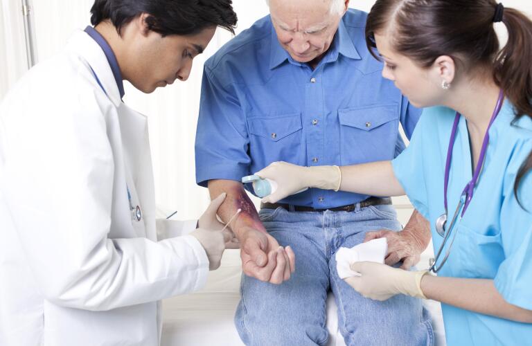 emergency room treatment of senior man's skin burn on forearm