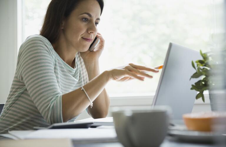 Businesswoman using technologies at desk in home office