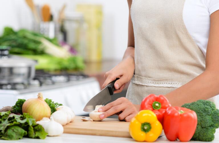Close up of hands slicing vegetables with knife