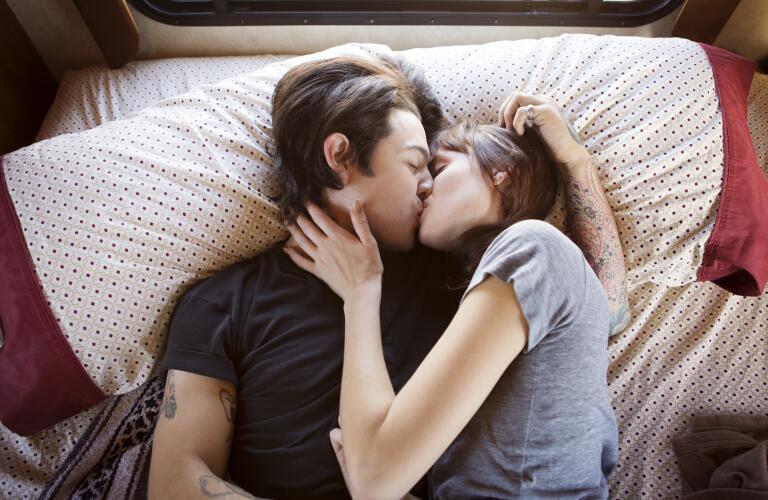 Young couple kissing while lying in bed