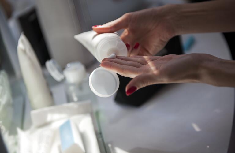 closeup of woman's hands using cosmetic cream in bathroom