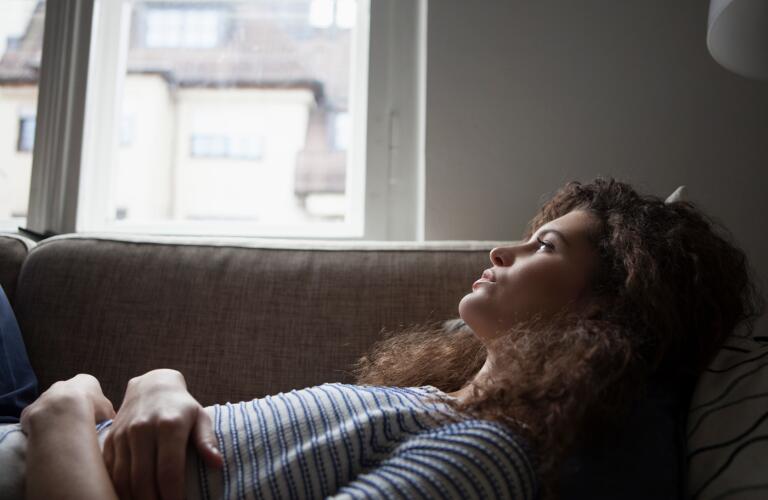 serious-young-woman-lying-on-sofa