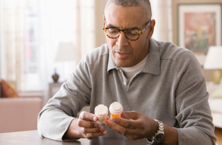 Mixed race man examining prescription bottles