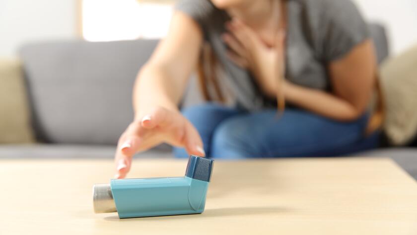 young woman reaching desperately for asthma inhaler