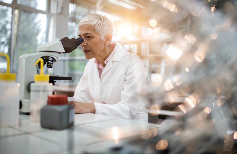 scientist looking into microscope in lab