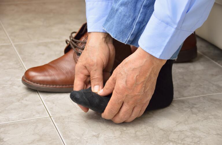 man bending over with foot pain