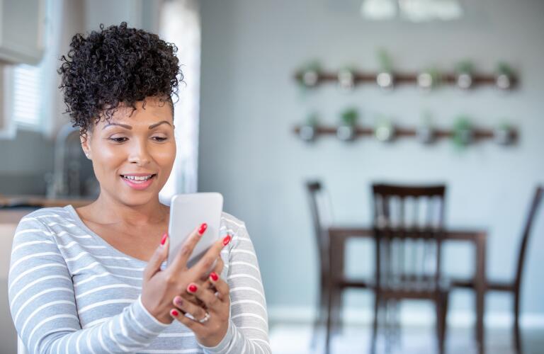 African American woman holding up smartphone for virtual doctor's appointment
