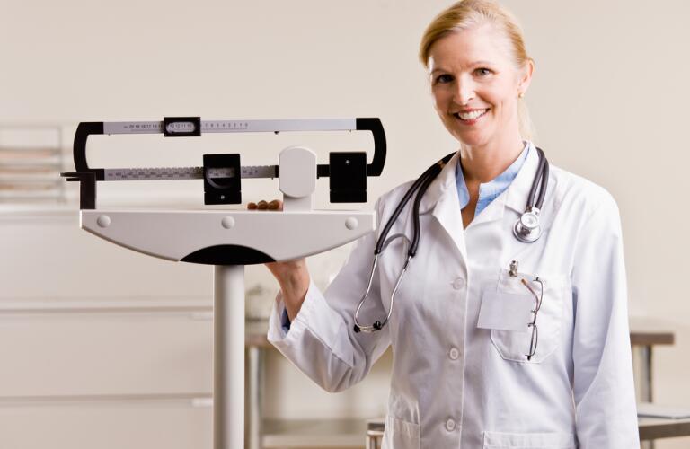 Women doctor standing by weight scale