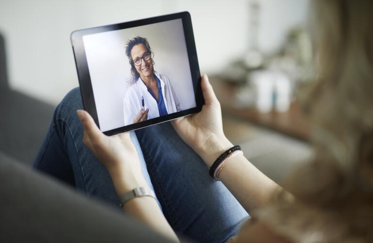 closeup of two hands holding computer tablet during telehealth appointment with doctor