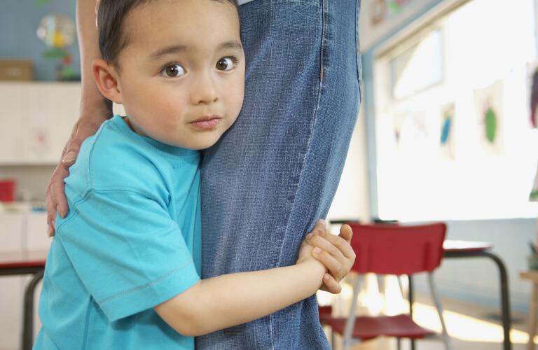 Shy young boy holding onto mother's leg