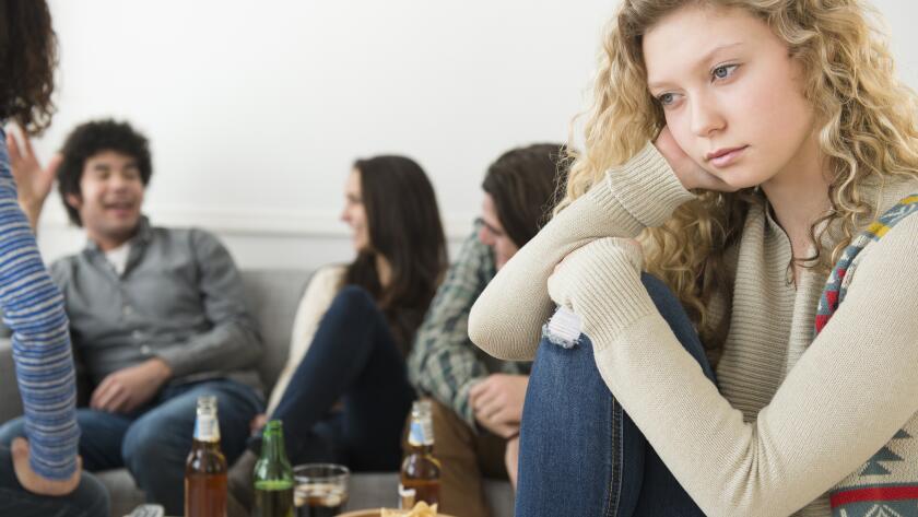 Young Caucasian girl looking lonely with group of friends in background