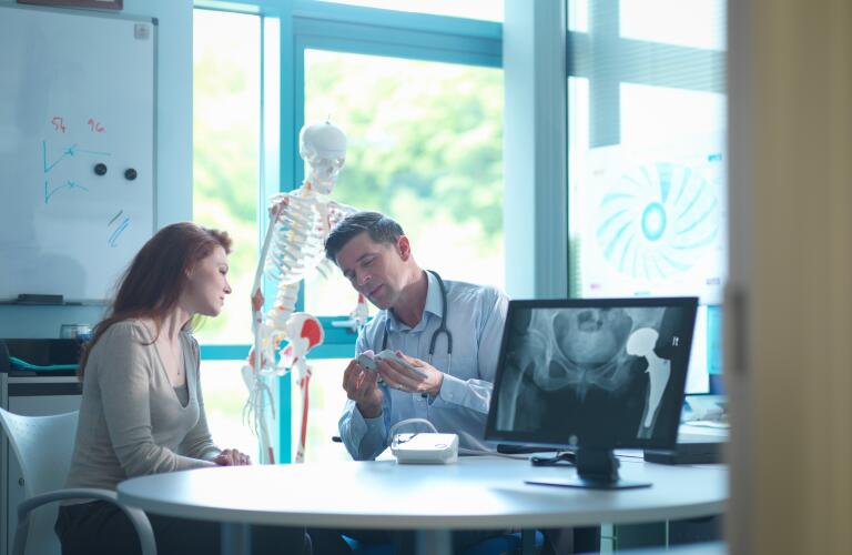 Young female Caucasian woman talking to male Caucasian doctor about artificial hip joint