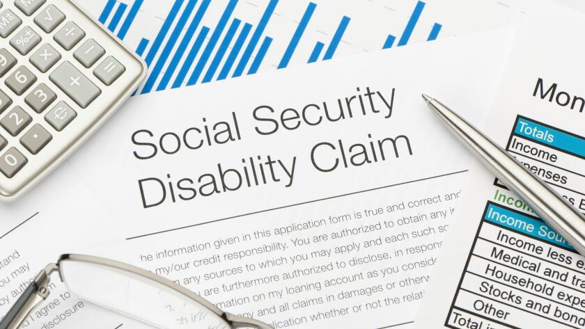 social security disability claim with calculator glass and pen