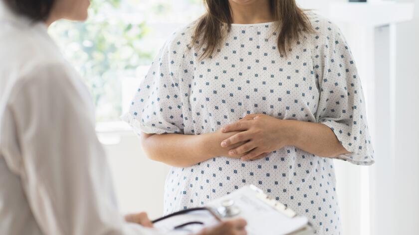 woman-in-patient-gown-listening-to-doctor