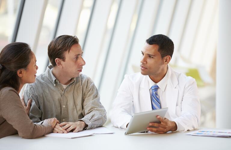 Doctor Using Tablet Computer Discussing Treatment With Patients