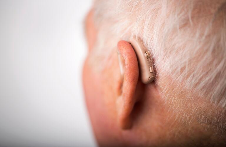 Senior man wearing hearing aid, close up