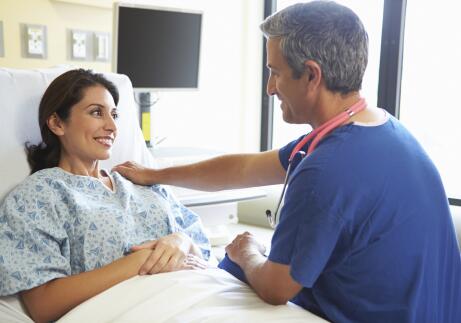 Male Nurse Talking With Female Patient In Hospital Room