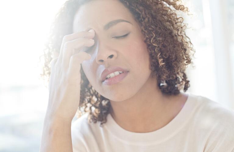 Young African American woman looking stressed holding hand to forehead with eyes closed
