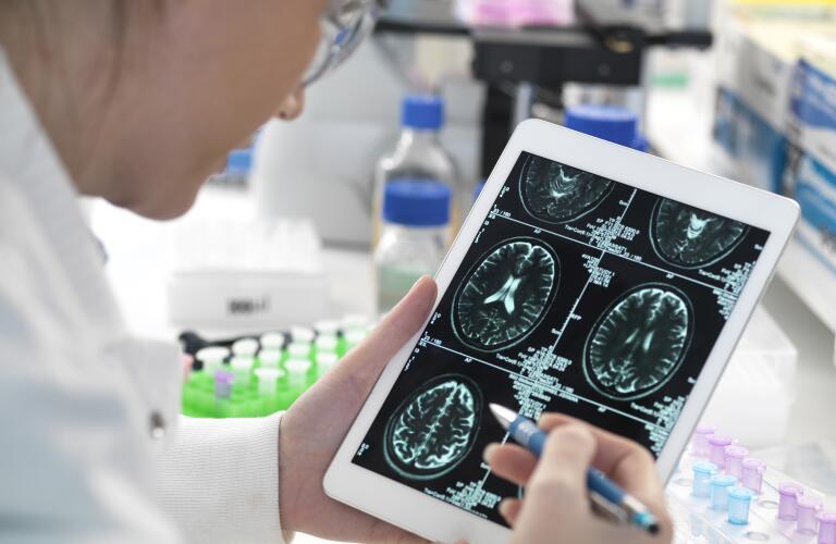 Doctor viewing patient's brain scan on digital tablet in laboratory, research or diagnosis concept