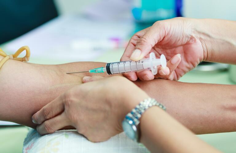 Doctor drawing blood sample from arm for blood test