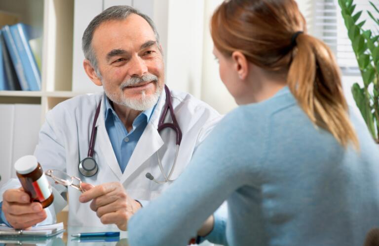 Male doctor with femail patient holding medicine bottle