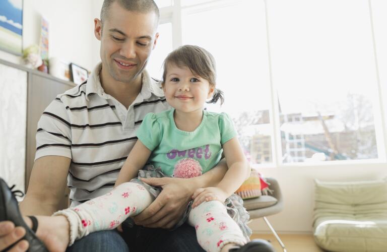 Father putting shoes on daughter