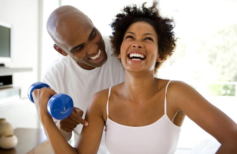 Man smiling at woman lifting weights