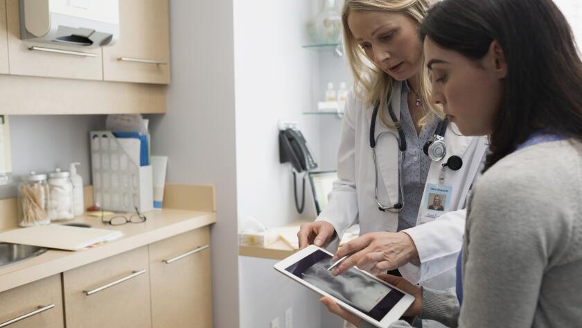 Female doctor showing patient digital tablet x-ray