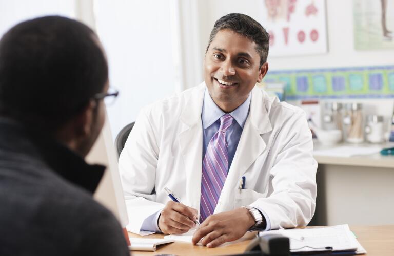 male doctor smiling and talking with male patient in office