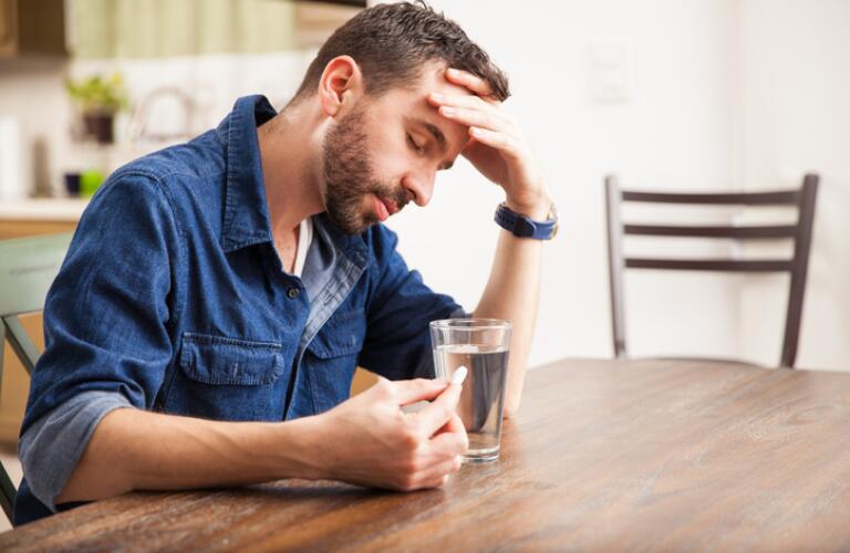 sick-man-sitting-at-table-with-pill-and-glass-of-water